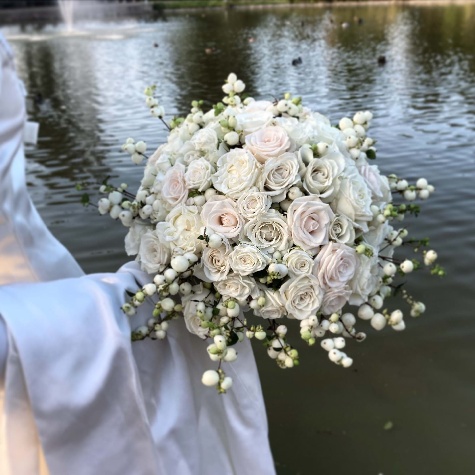 Rund og hvid brudebuket med sø i baggrunden