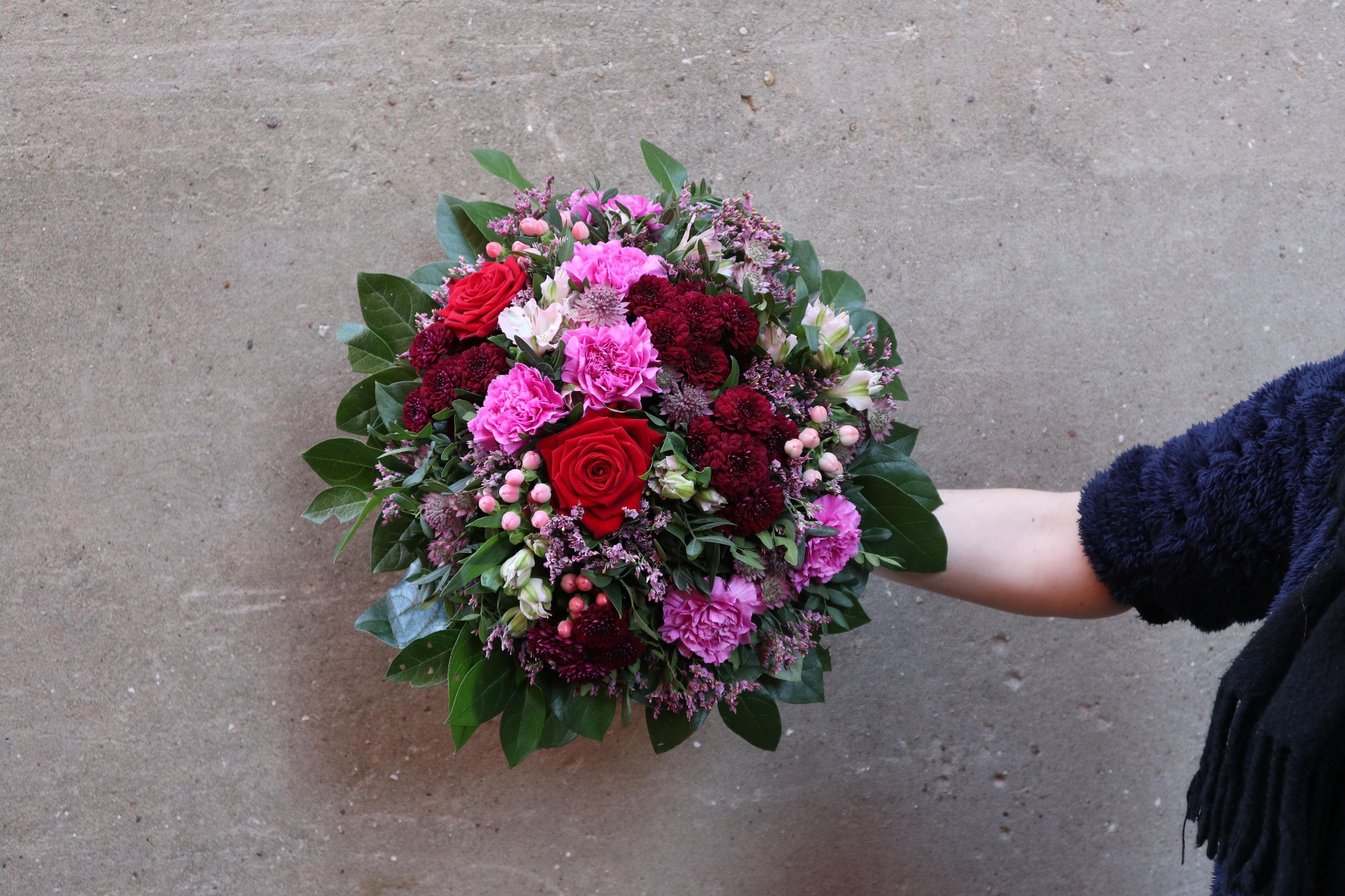 Romantisk buket med blomster i røde, lilla og lyserøde farver. 