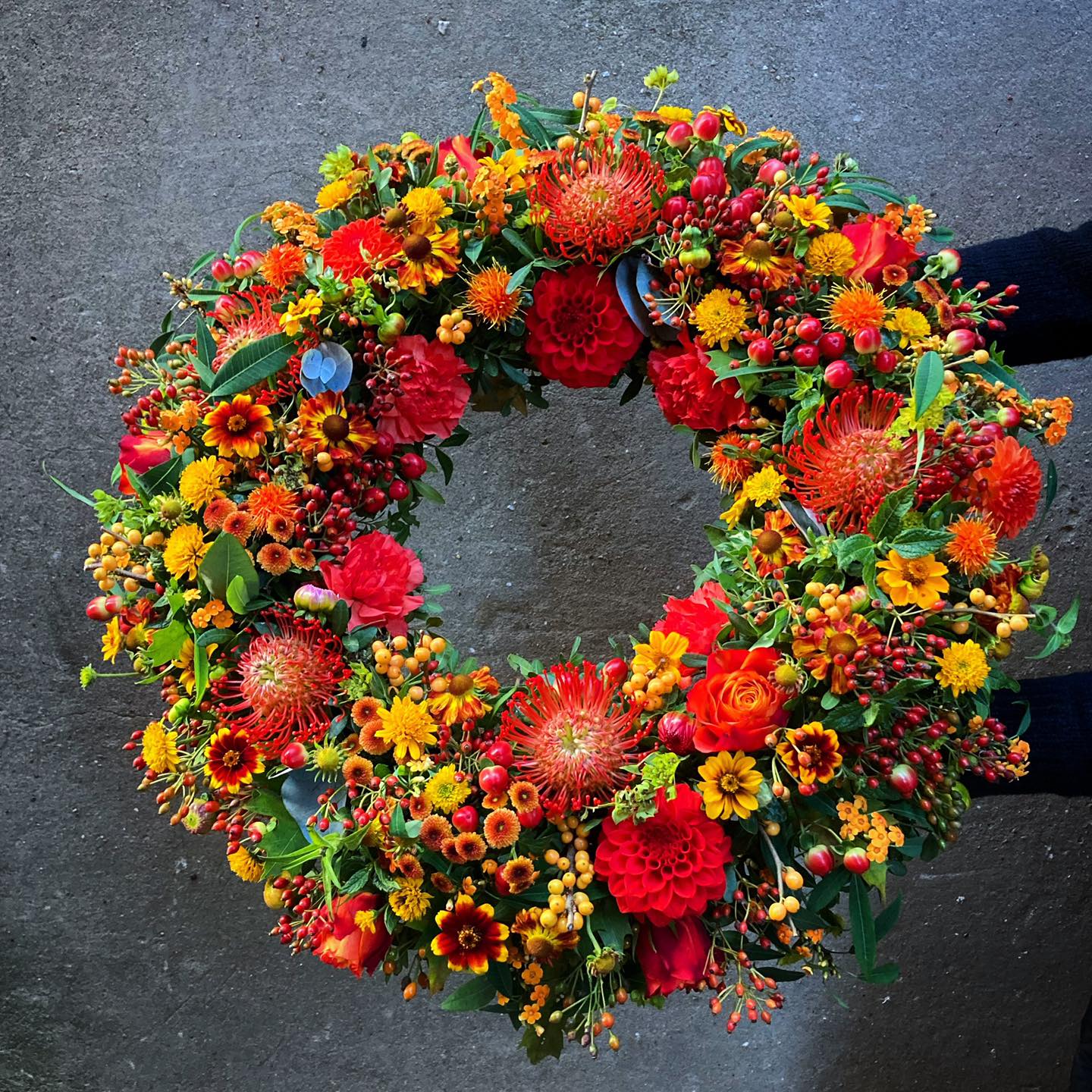 Begravelseskrans bundet med efterårsblomster i varme og stærke farver. 