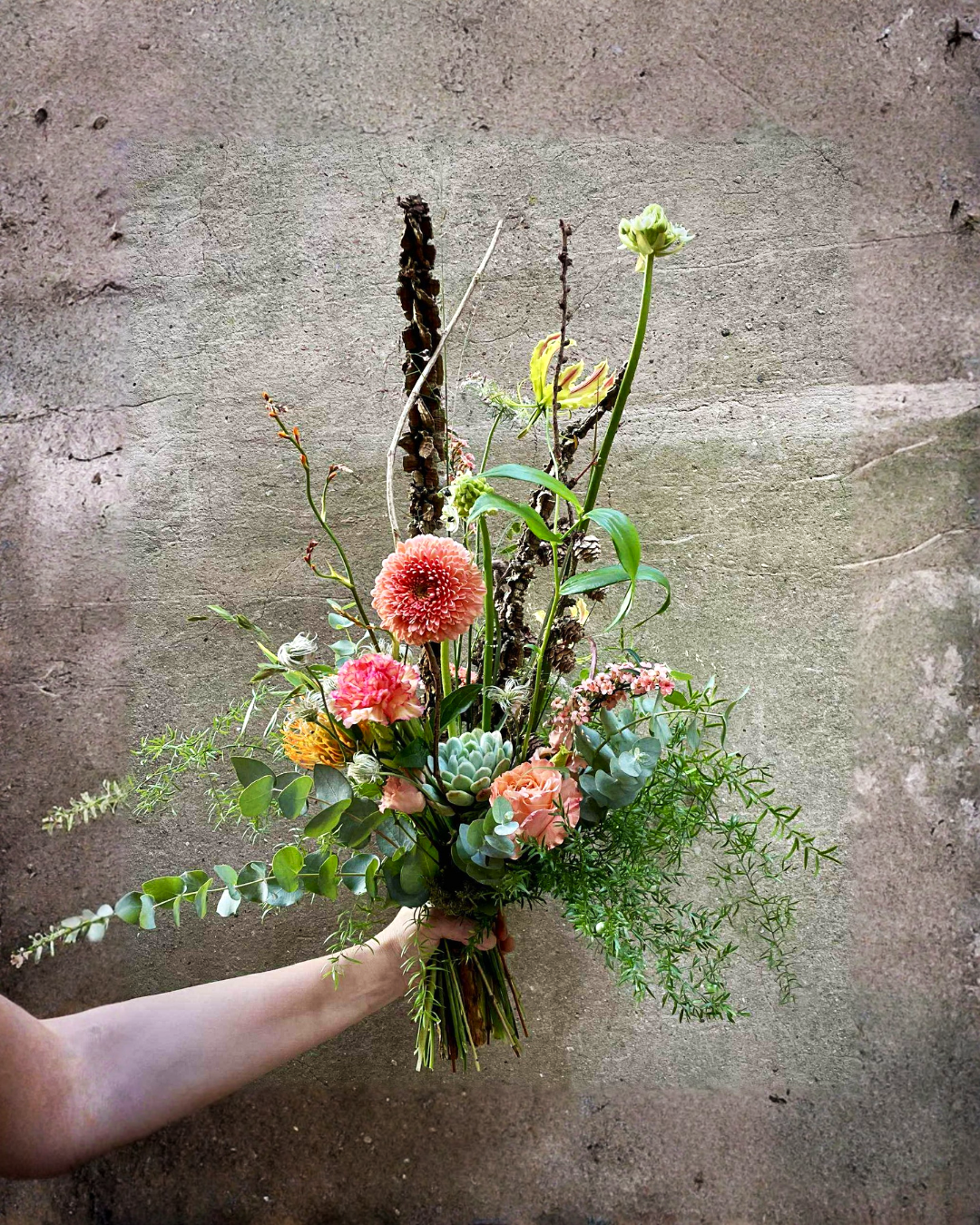 Høj og luftig buket med blomster i årstidens farver. 