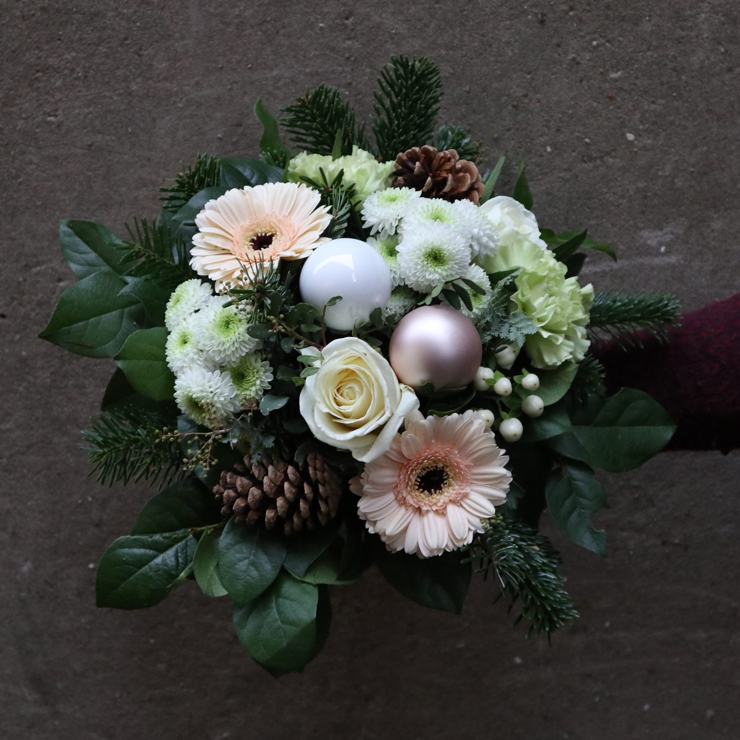 Tæt julebuket med julekugler og hvide creme blomster. 