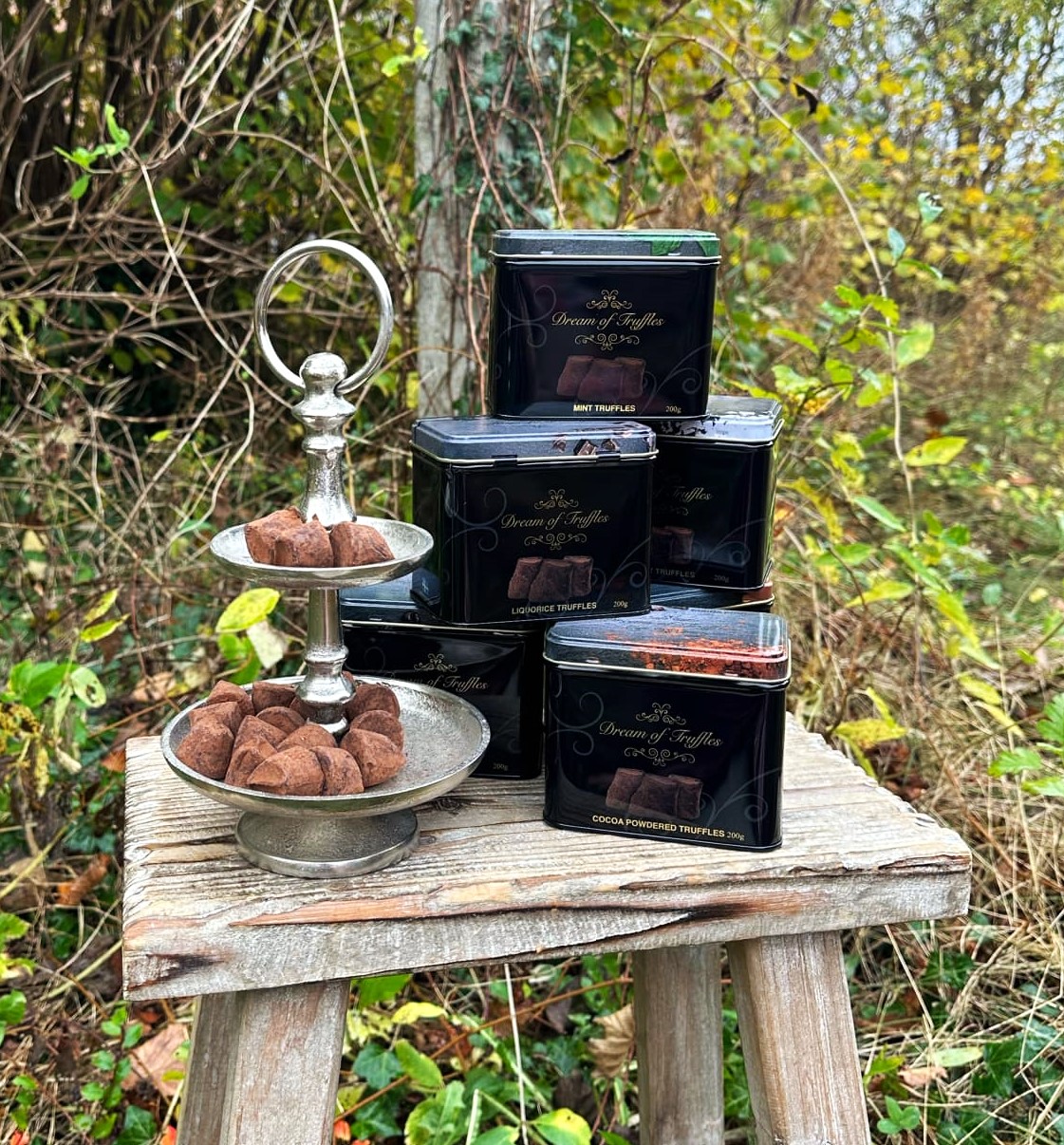 Trøffelchokolader med forskellige smage står på en rustik træskammel. 