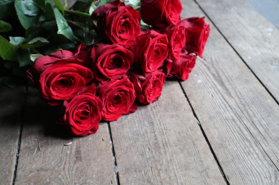 Smukke røde roser ligger på en et rustikt plankebord. 