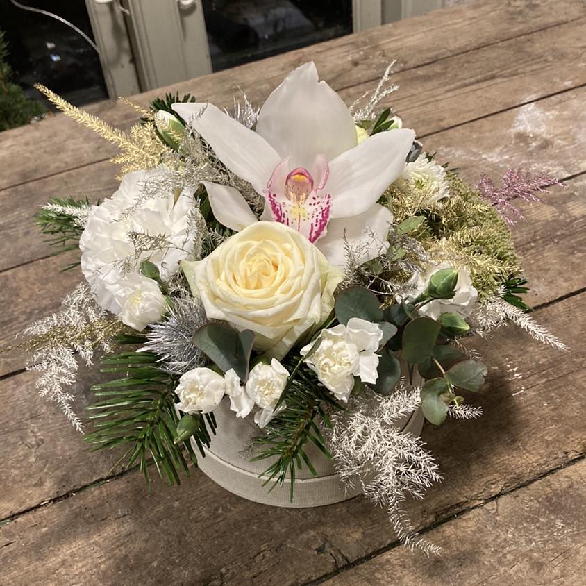 Hatteæske stukket med hvide blomster og pyntet med vintergrønt. 