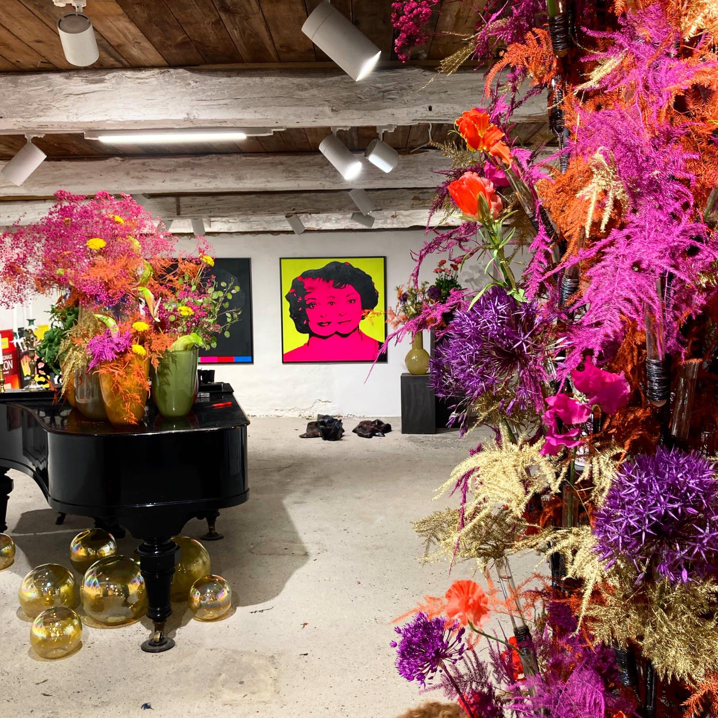 Studio fyldt med farverigt blomsterkunst i skarp lilla, rød, orange og neon. 