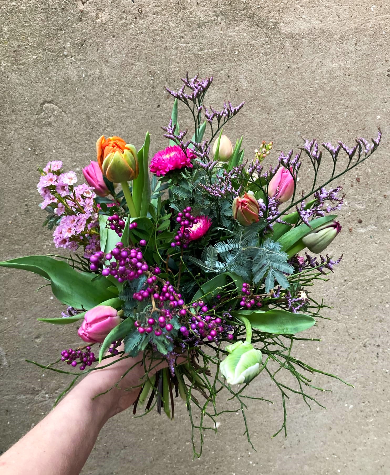 Livlig og farverig buket med årtidens blomster i lilla, lyserøde og orange nuancer. 