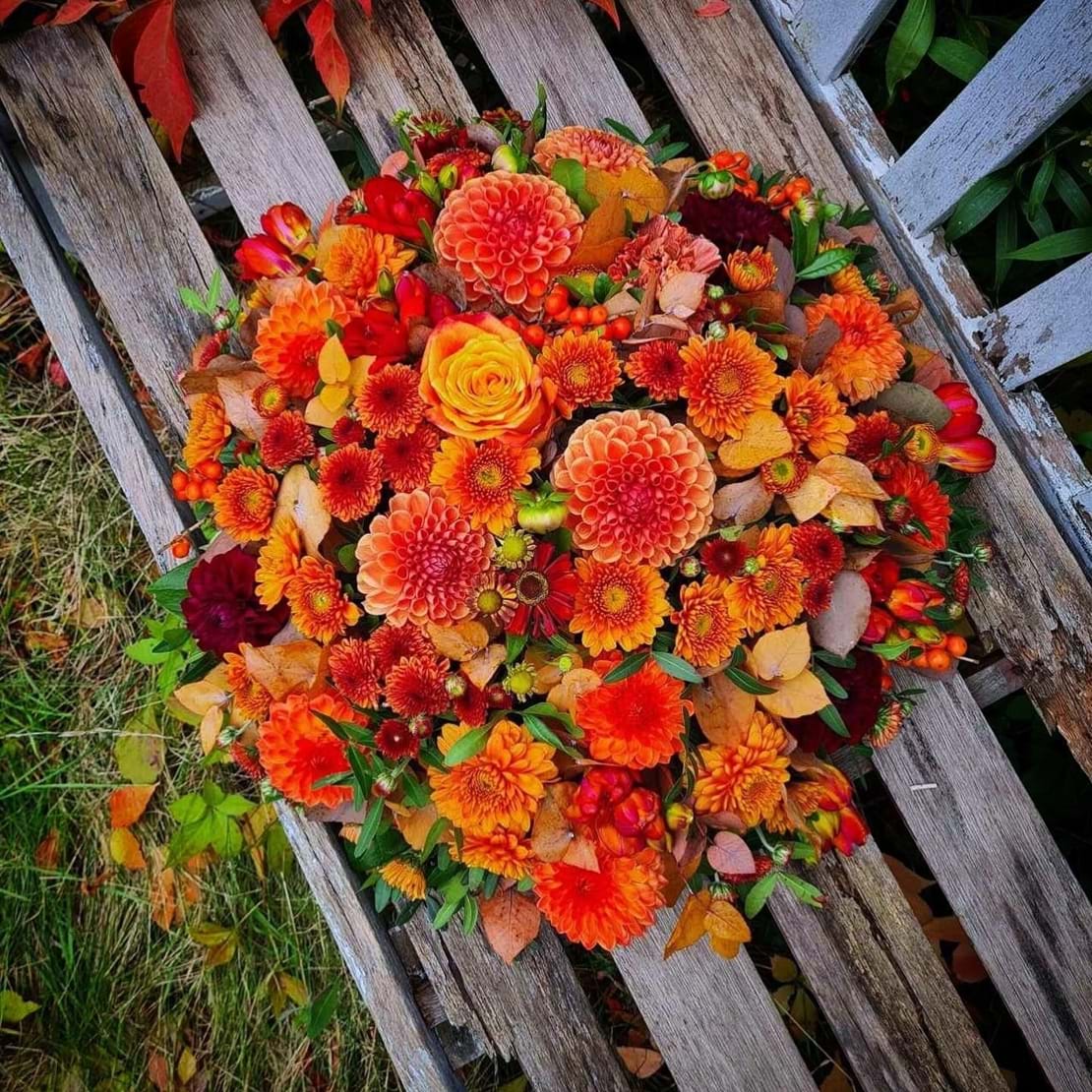 Begravelsespude bundet med efterårsblomster i varme farver.