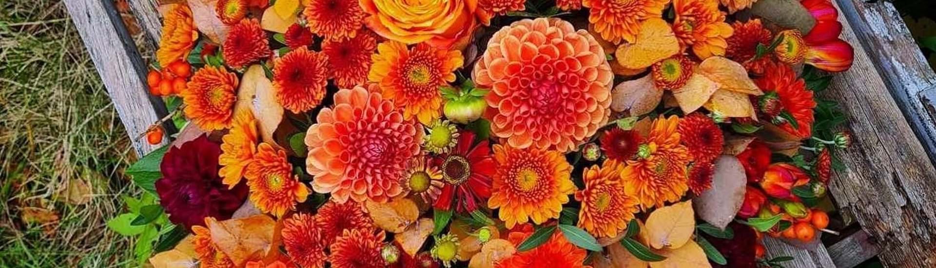 Blomsterpude med blomster i varme orange, røde og gule efterårsfarver.