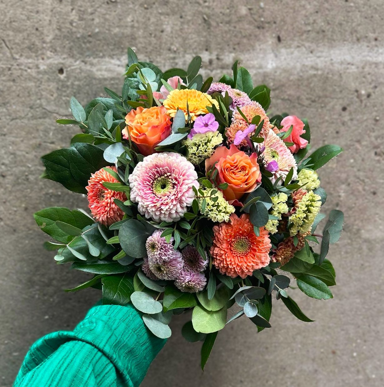 Tæt buket bundet med blomster i forskellige pastelfarver. 