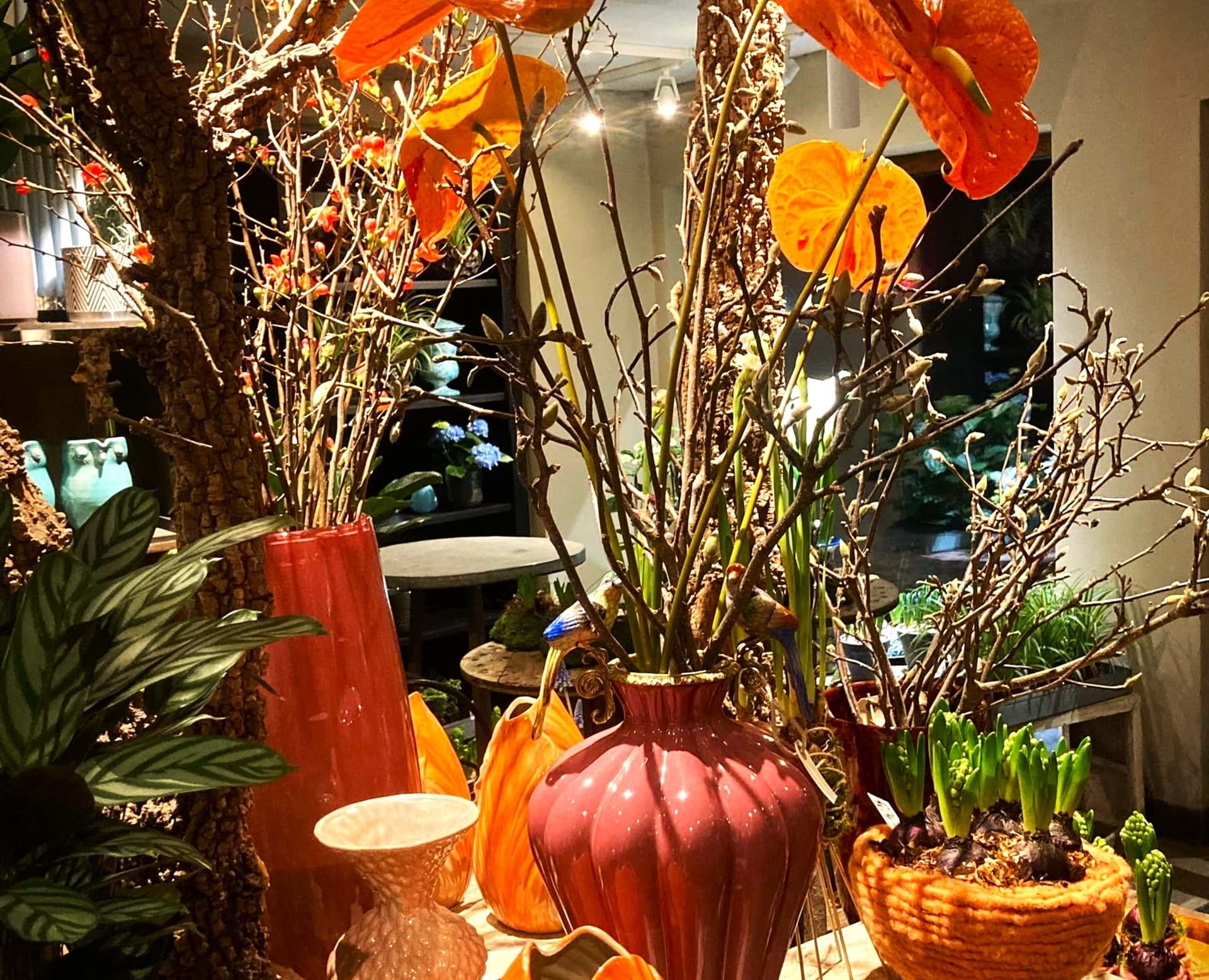 Dekoreret bord i butikken med orange og røde nuancer i vaser.
