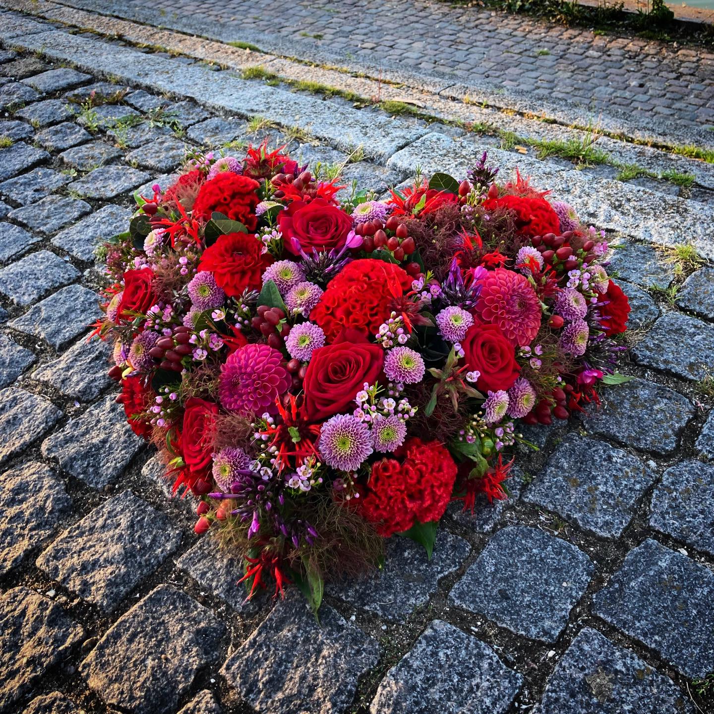 Begravelseshjerte med blomster i røde, rosa og lilla nuancer. 